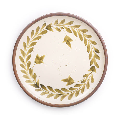 Large round ceramic platter with a hand-painted olive green leaf wreath and floral design on a cream background with an exposed clay rim.