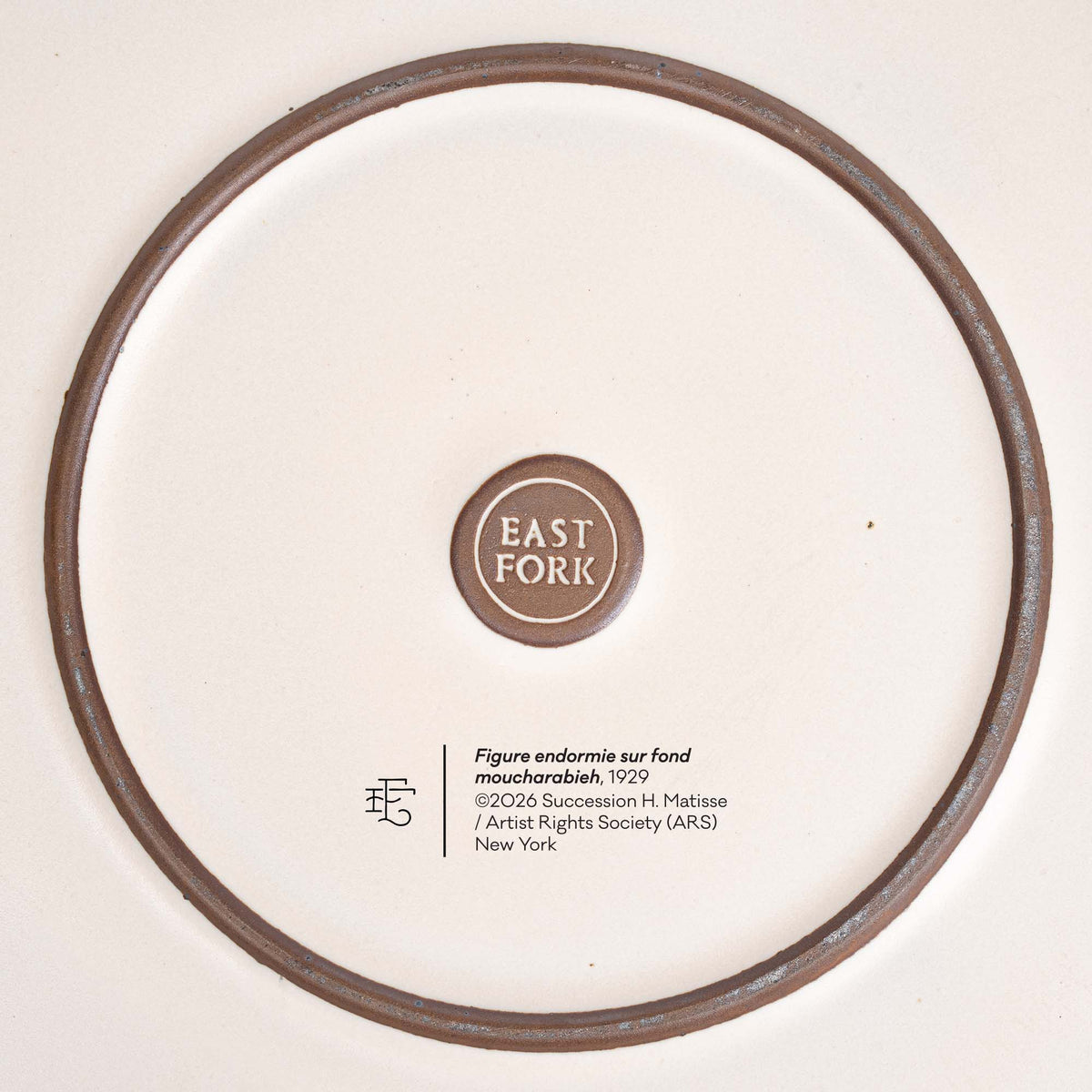 The underside of a ceramic serving platter by EAST FORK with the copyright and title of Henri Matisse's artwork, Figure endormie sur fond moucharabieh.
