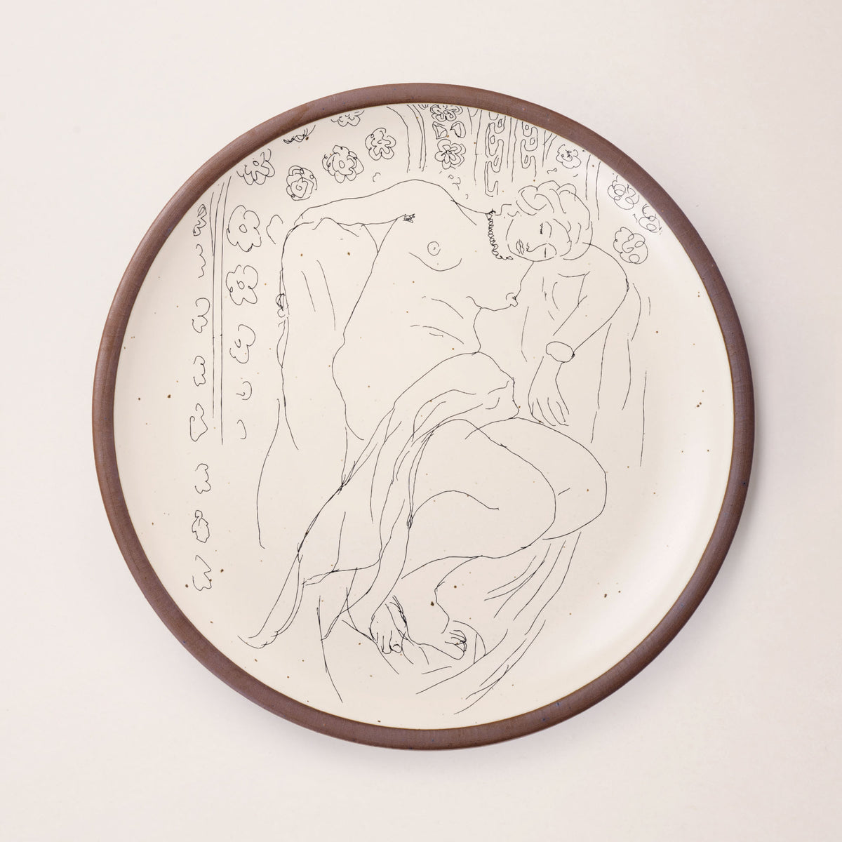 A large serving platter in a warm off-white color with unglazed rim with a black decal of the artwork, Figure endormie sur fond moucharabieh, from Henri Matisse.