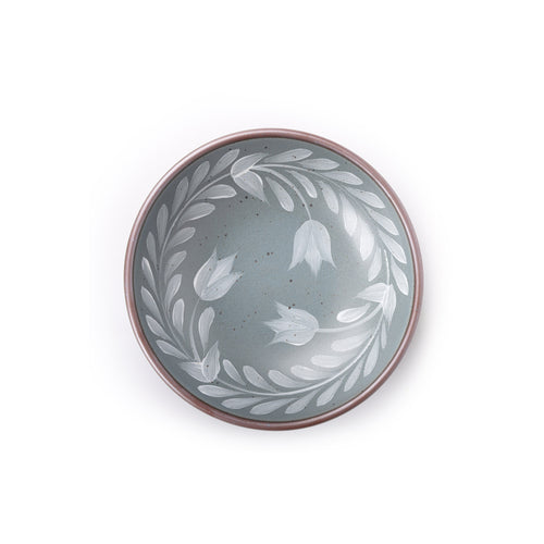 Overhead view of a Medium ceramic shallow bowl with a hand-painted white leaf border on a blue-grey interior and exterior with an exposed clay rim.