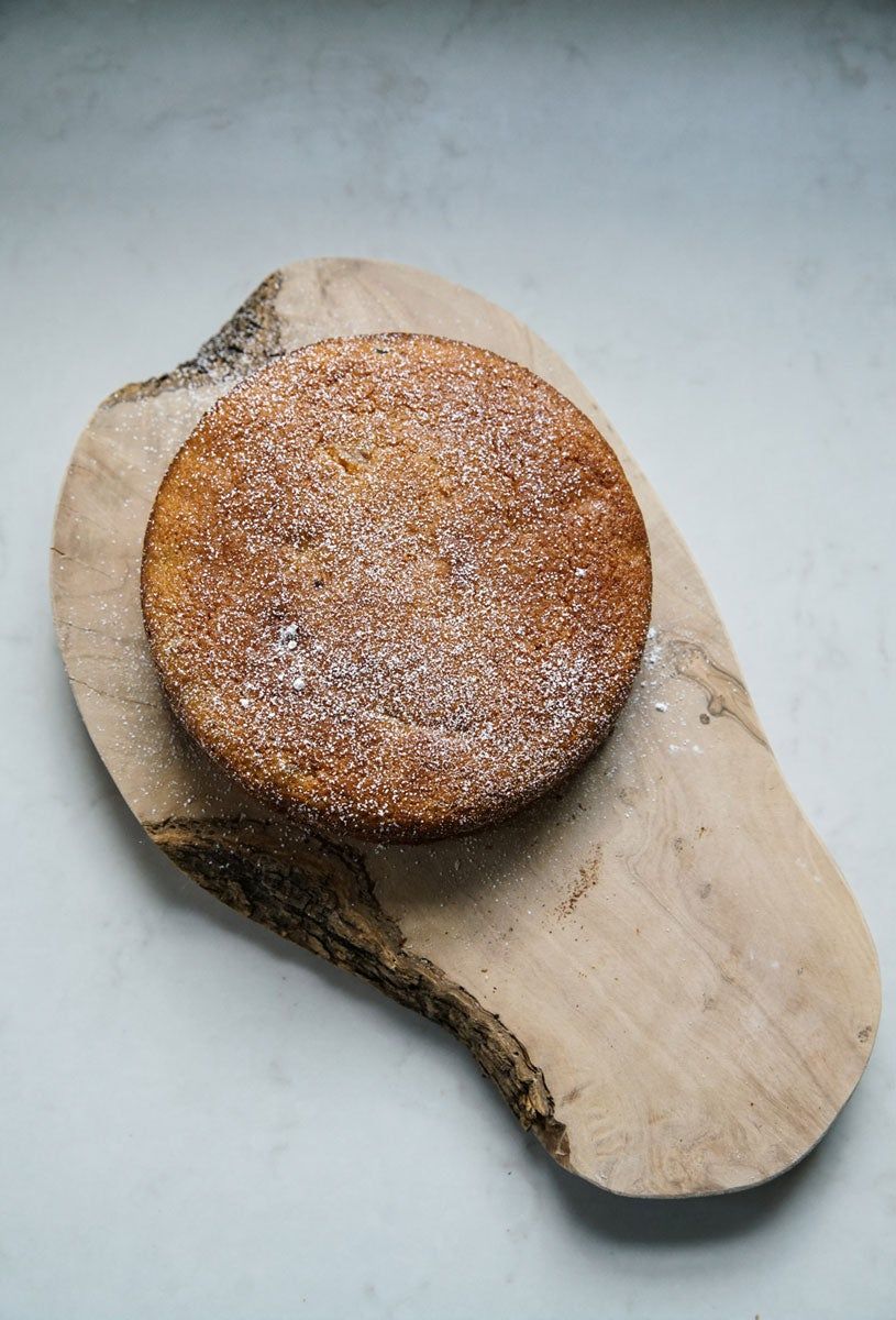A round wheat cake sitting on a curvy shaped wooden board