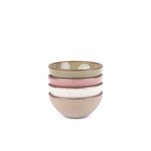 A stack of 4 small dessert sized rounded ceramic bowls in a reflective dappled grey-green, warm off-white, dusty mauve pink and warm pale brown colors featuring iron speckles and an unglazed rim