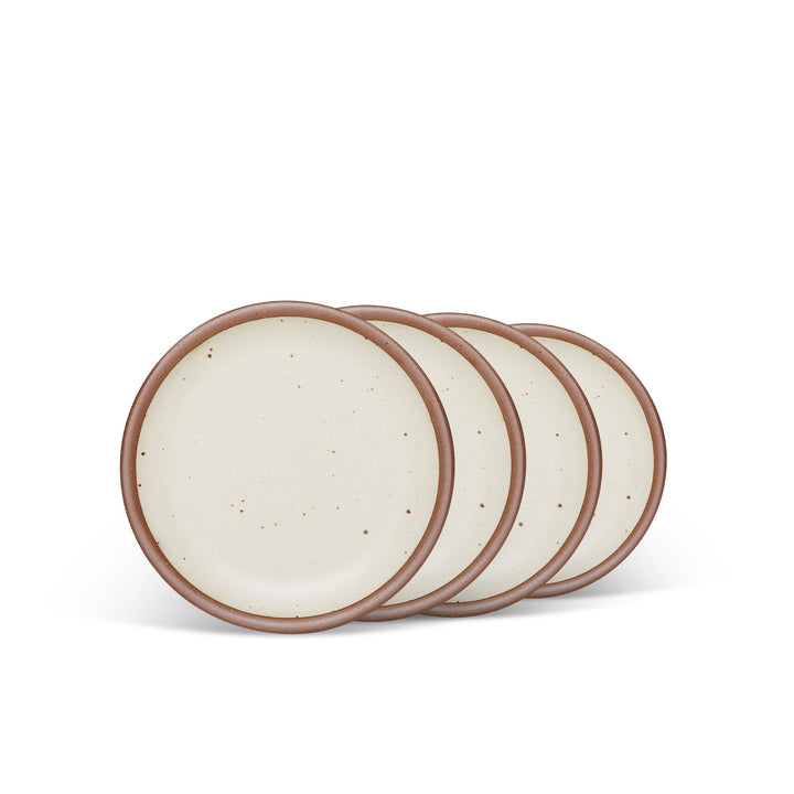 4 dessert sized ceramic plates in a warm, tan-toned, off-white color featuring iron speckles and an unglazed rim.