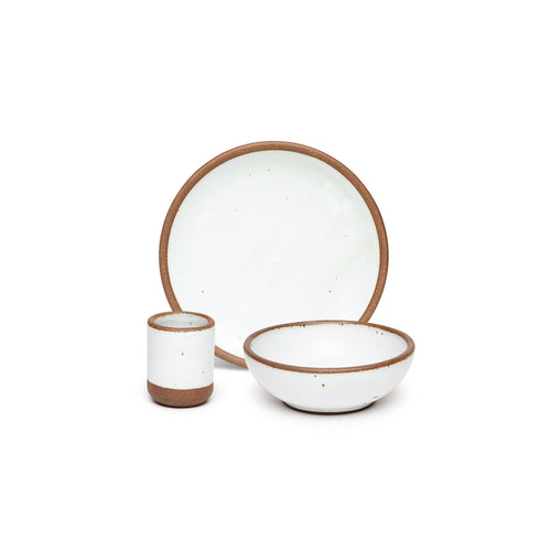A small tiny cup, a medium sized plate, and a small breakfast bowl paired together in a cool white color featuring iron speckles.