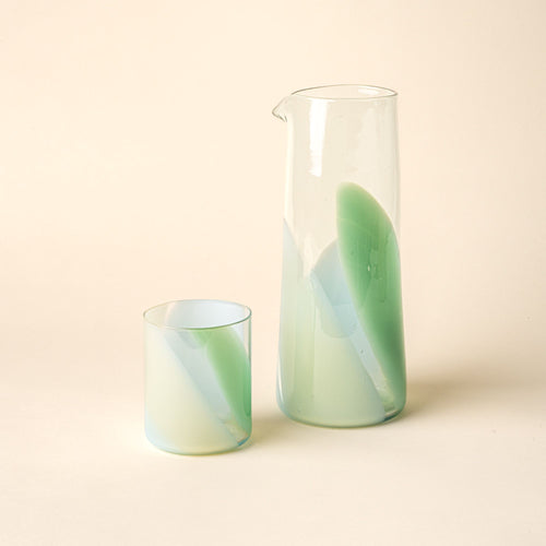 Hand-blown glass carafe and matching tumbler featuring a soft pastel green swirl design, displayed against a neutral background.