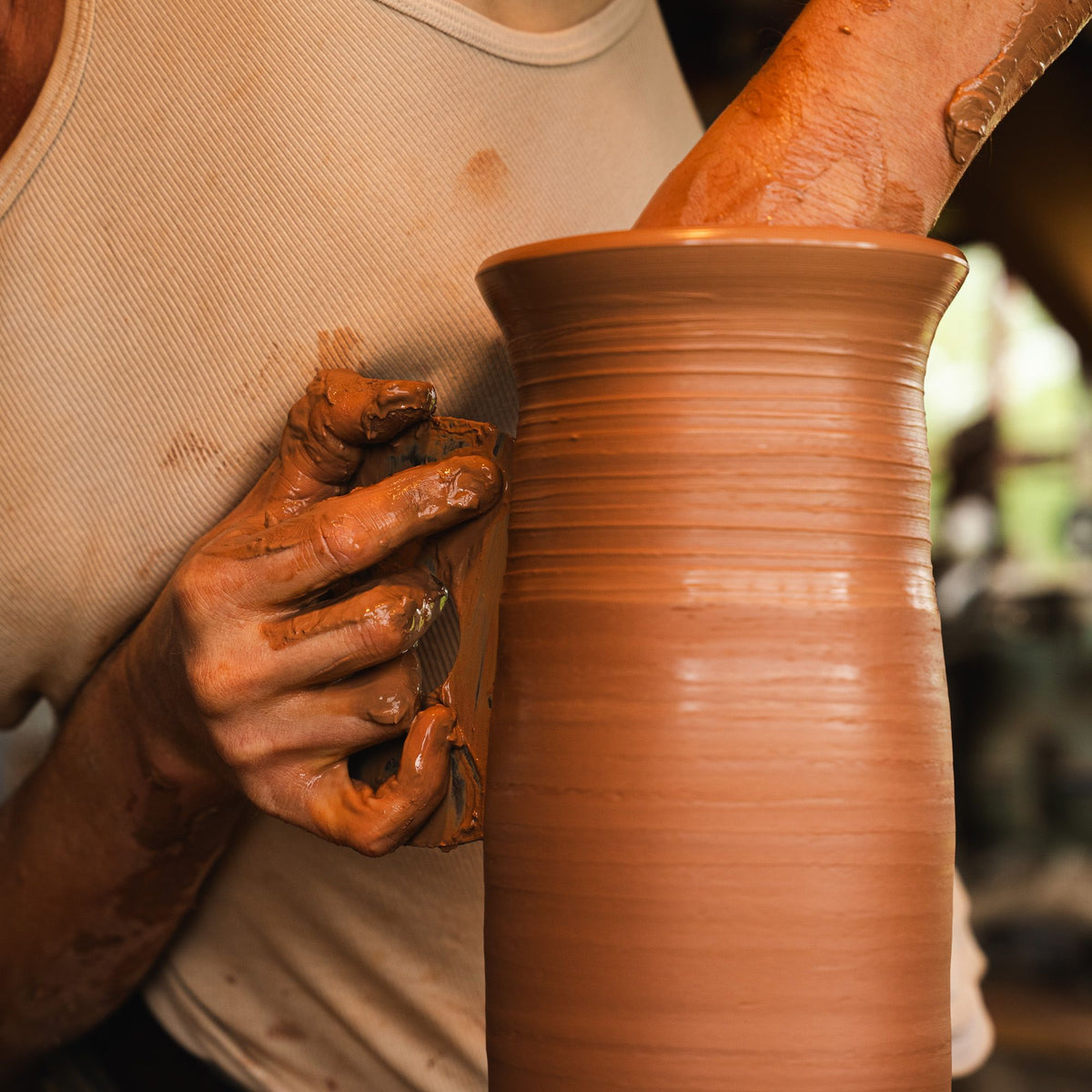 A closeup of John forming a Pitcher on the wheel.