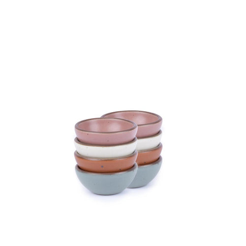 A stack of 8 tiny rounded ceramic bowls in a cool terracotta, warm off-white, blue-grey and dusty mauve pink colors featuring iron speckles and an unglazed rim