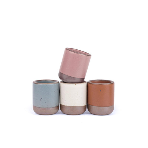 A set of 4 small, short ceramic mug cups in a cool terracotta, warm off-white, blue-grey, and dusty mauve pink colors featuring iron speckles and unglazed rim