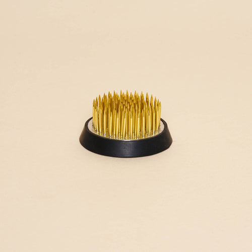 A small "kenzan" – a pin frog made of brass spikes on a flat circular base to assist in flower arrangements.