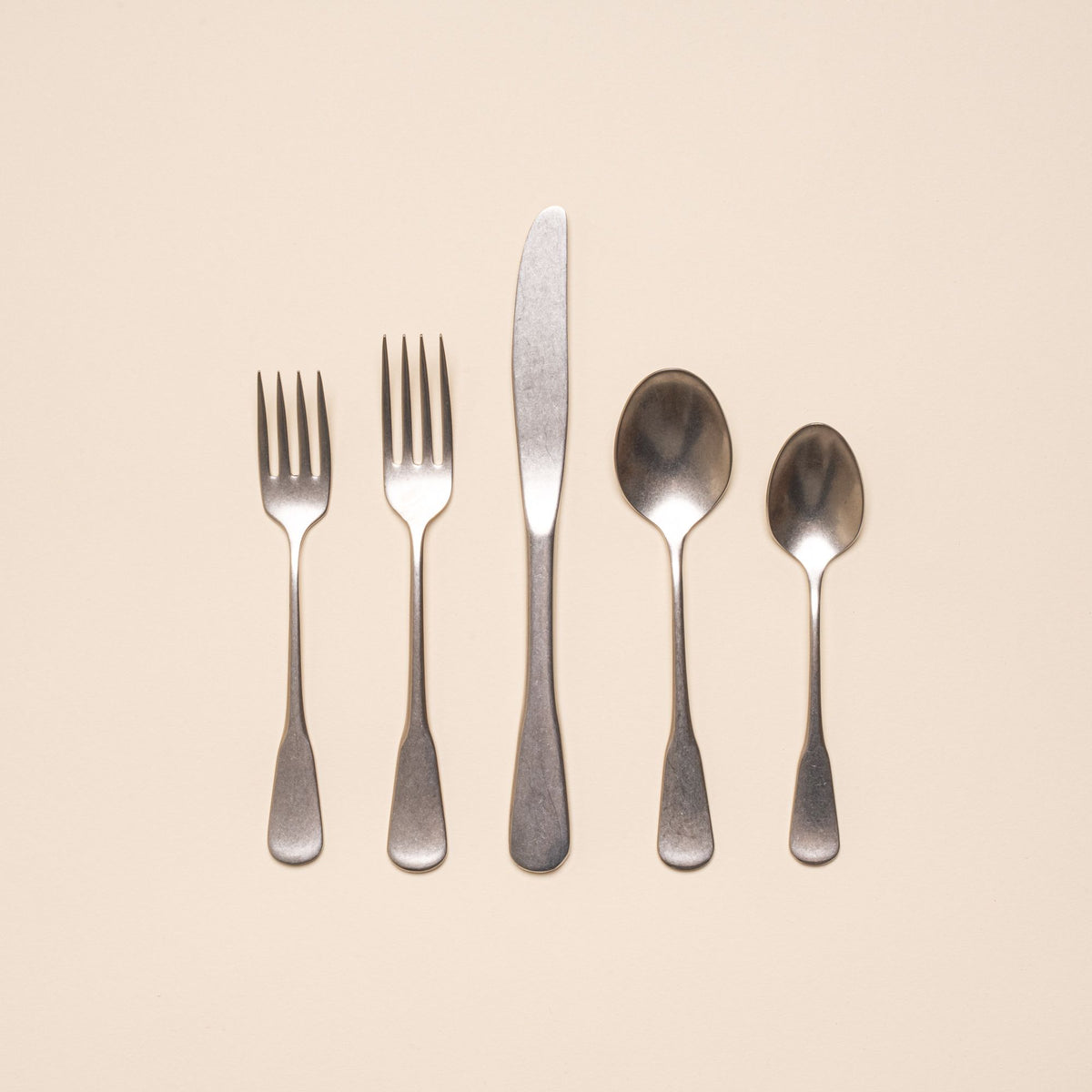 A stainless steel five-piece flatware including 2 forks, 2 spoons, and 1 knife, in a tumbled matte finish and classic design