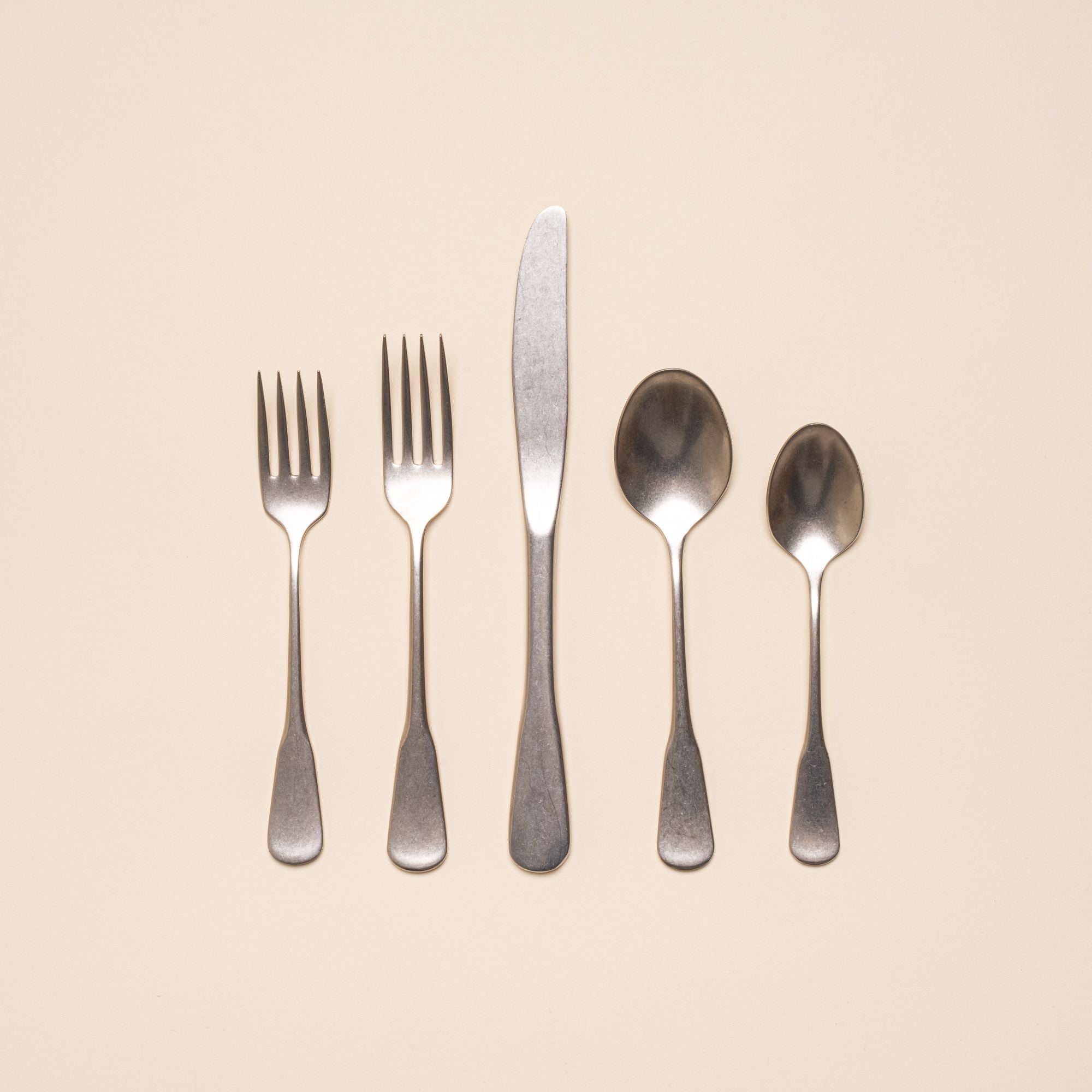 A stainless steel five-piece flatware including 2 forks, 2 spoons, and 1 knife, in a tumbled matte finish and classic design