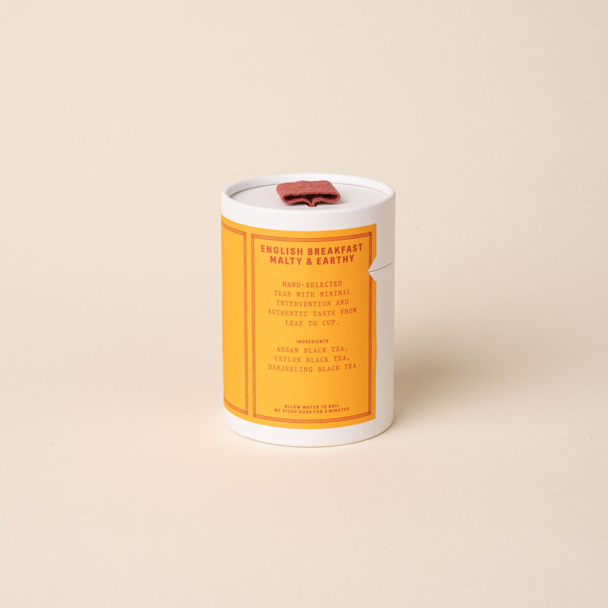 RAAZI English Breakfast tea tin with a bright orange label and red pull tab, photographed on a soft neutral backdrop.