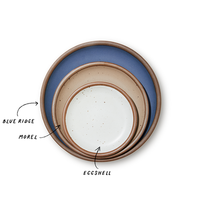 A stack of 3 plates in Dinner, Side, and Cake sizes in a navy, warm light brown, and white colors.