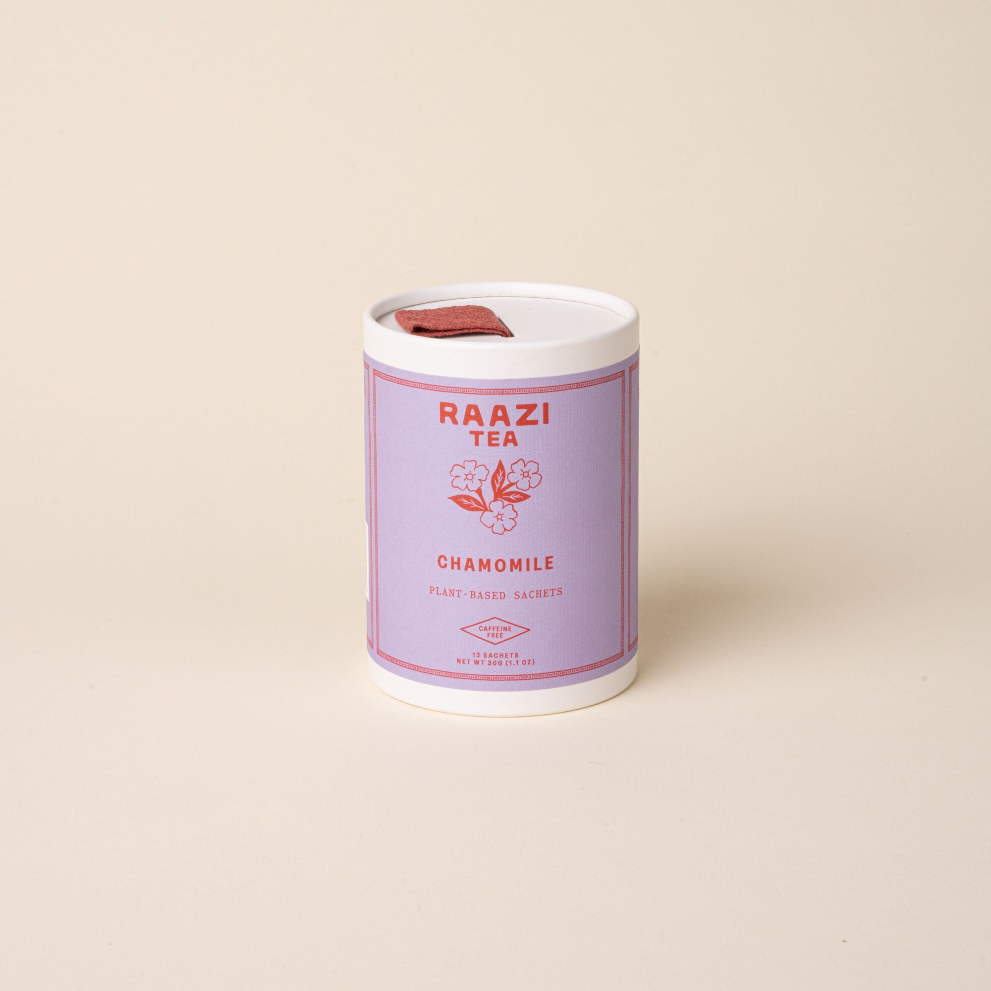 A white cylindrical tin of RAAZI Tea labeled ‘Chamomile’ with a lavender label and red text, topped with a small red pull tab, photographed on a pale beige background.