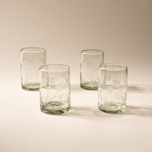 Four clear tumbler glasses made of recycled glass with etched thistle designs on it