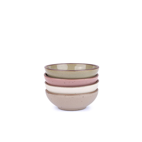 A stack of 4 small shallow ceramic bowls in a reflective dappled grey-green, warm off-white, warm pale brown, dusty mauve pink colors featuring iron speckles and an unglazed rim