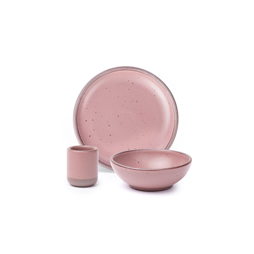 A small tiny cup, a medium sized plate, and a small breakfast bowl paired together in a dusty mauve pink color featuring iron speckles