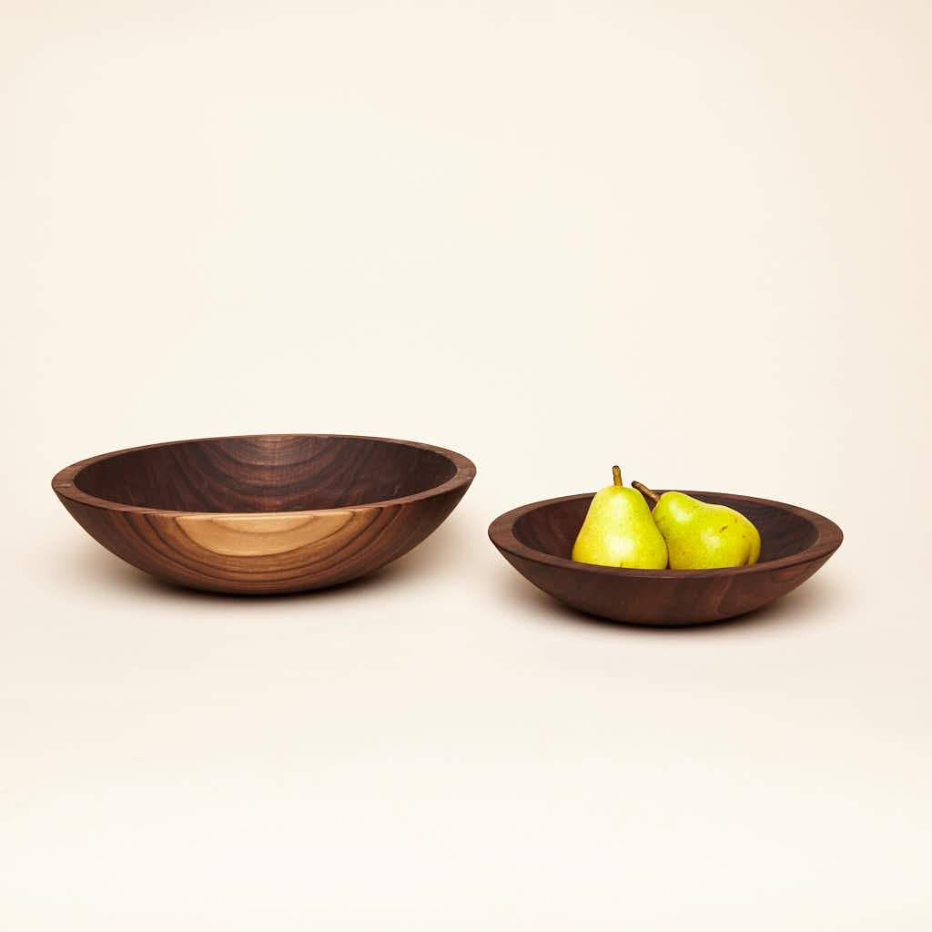 Two shallow walnut wood nesting bowl, 1 small with 2 pears sitting inside, a 1 medium sized