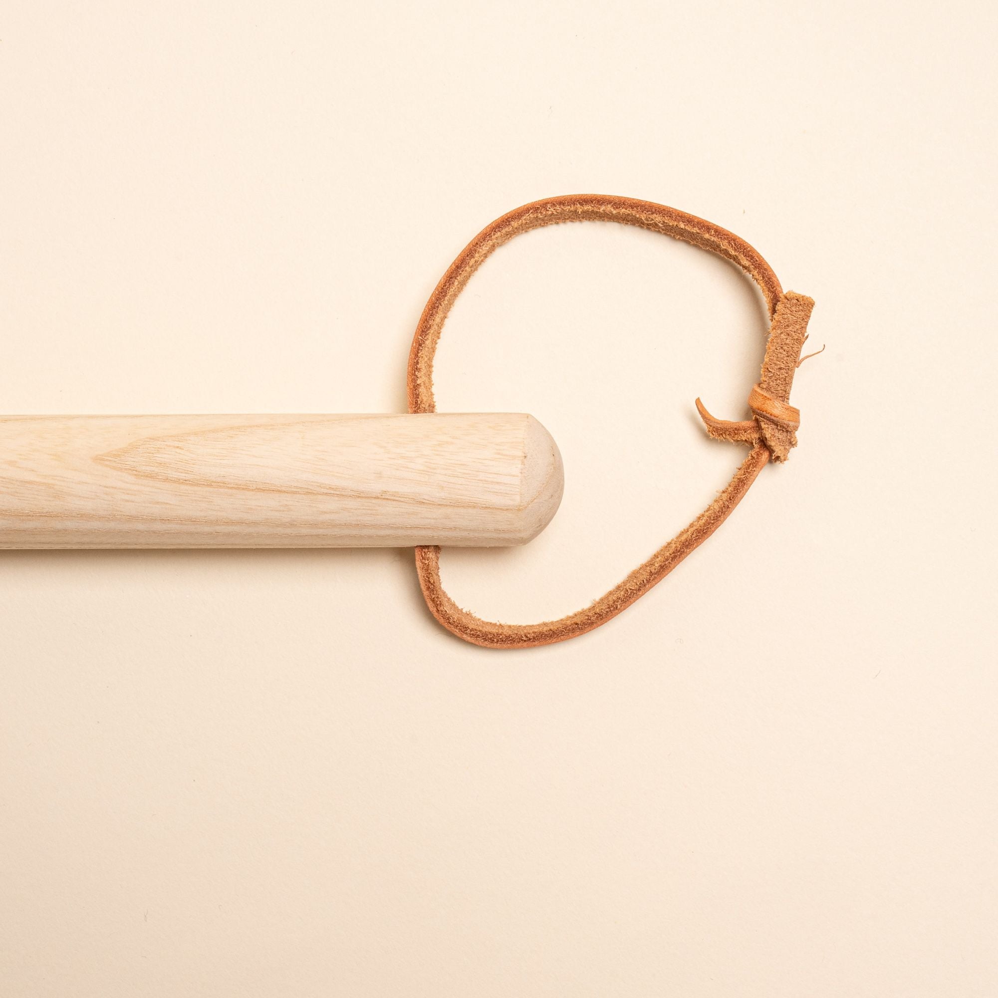 The top of a wood broom, with a leather cord loop for hanging.