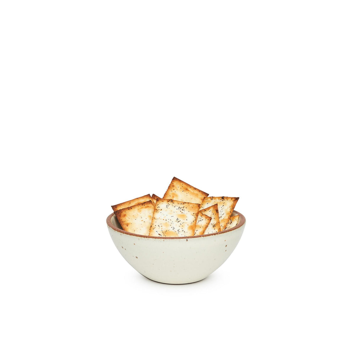 A small dessert sized rounded ceramic bowl in a warm, tan-toned, off-white color featuring iron speckles and an unglazed rim, filled with crackers