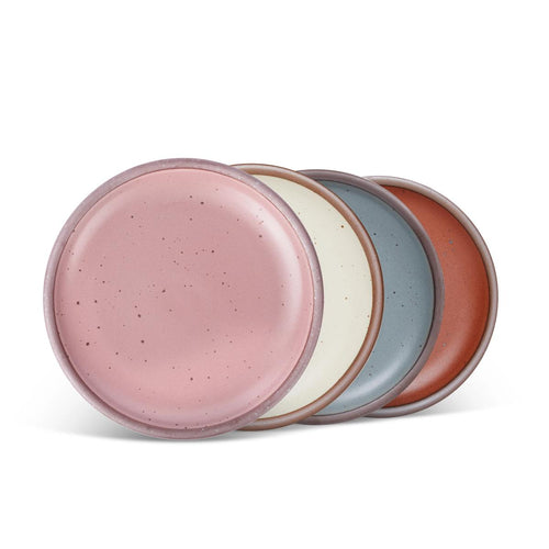 4 medium sized ceramic plates in a dusty mauve pink, blue-grey, and cool terracotta colors featuring iron speckles and an unglazed rim.
