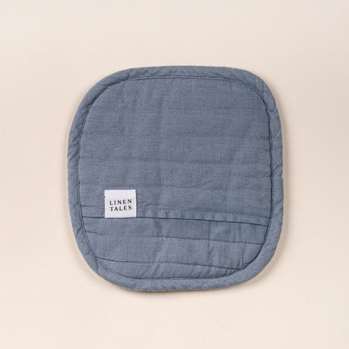 Square quilted linen potholder in a blue-grey color with rounded corners and a small ‘LINEN TALES’ label, on a light background.