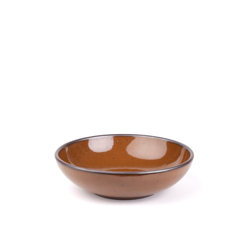 A dinner-sized shallow ceramic bowl in a glossy caramel brown color featuring iron speckles and an unglazed rim
