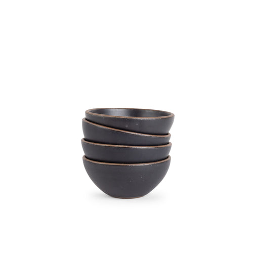 A stack of 4 small dessert sized rounded ceramic bowls in a graphite black color featuring iron speckles and an unglazed rim