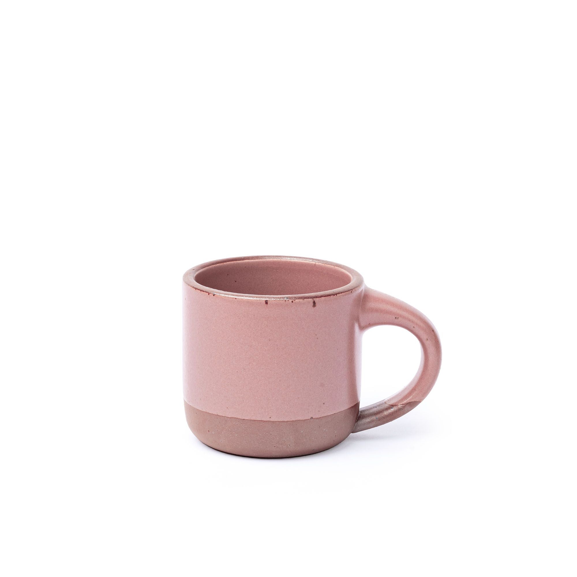 A small sized ceramic mug with handle in a dusty mauve pink glaze featuring iron speckles and unglazed rim and bottom base.