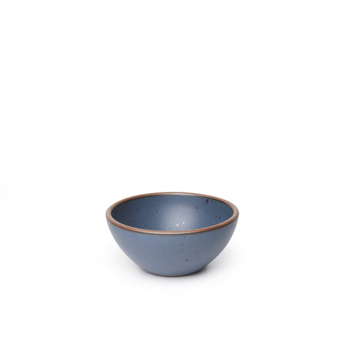A small dessert sized rounded ceramic bowl in a cool medium blue color featuring iron speckles and an unglazed rim
