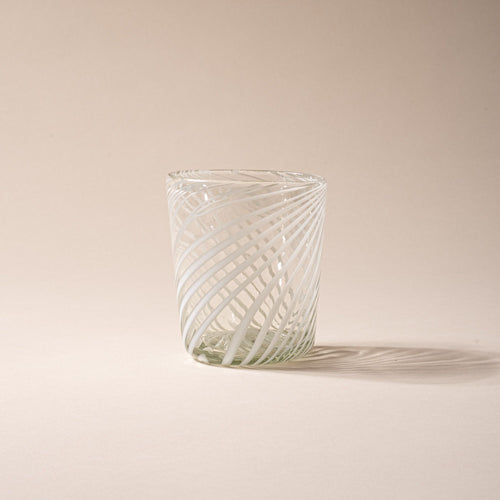 Clear glass tumbler with white diagonal swirl pattern against a neutral background.