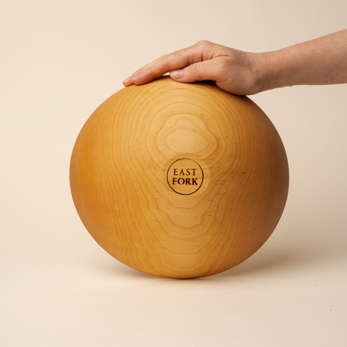 The bottom of a medium maple wood bowl with a stamp that reads "East Fork"