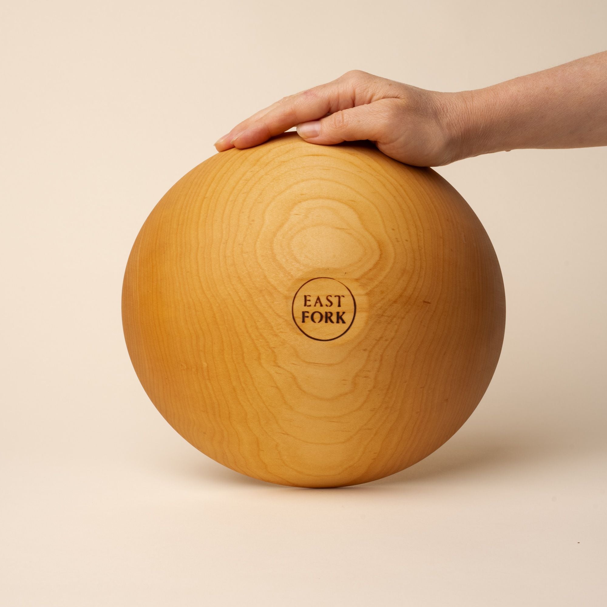 The bottom of a medium maple wood bowl with a stamp that reads "East Fork"