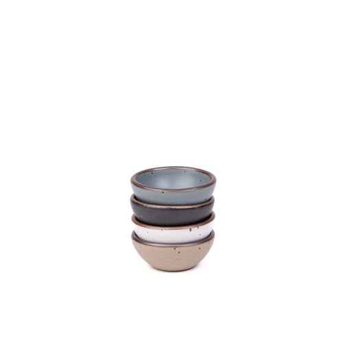 A stack of 4 tiny rounded ceramic bowls in a blue-grey, graphite black, cool white, and warm pale brown colors featuring iron speckles and an unglazed rim