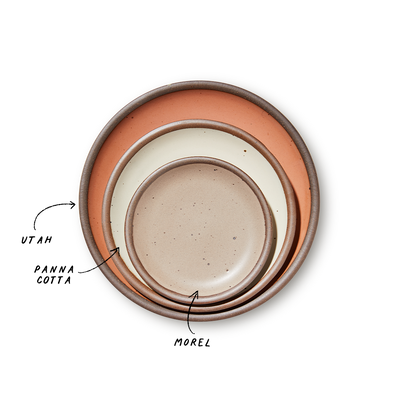 A stack of 3 plates in Dinner, Side, and Cake sizes in a peach, warm off-white, and warm pale brown colors.