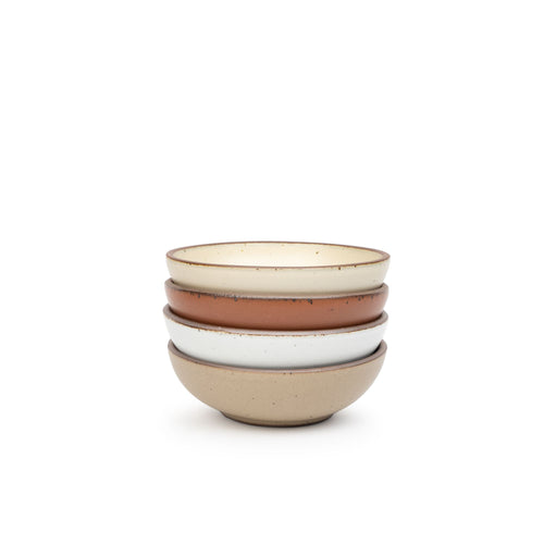A stack of 4 small shallow ceramic bowls in a cool terracotta, warm off-white, cool white, and warm pale brown colors featuring iron speckles and an unglazed rim