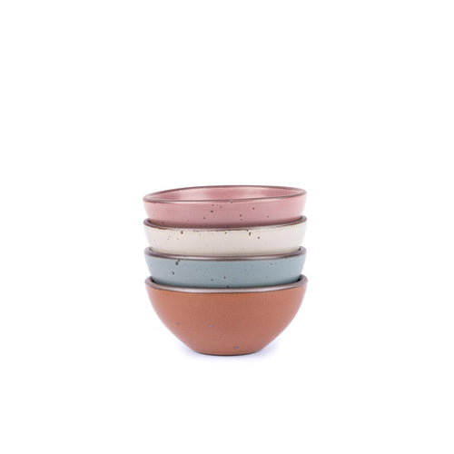 A stack of 4 small dessert sized rounded ceramic bowls in a cool terracotta, warm off-white, dusty mauve pink and blue-grey colors featuring iron speckles and an unglazed rim