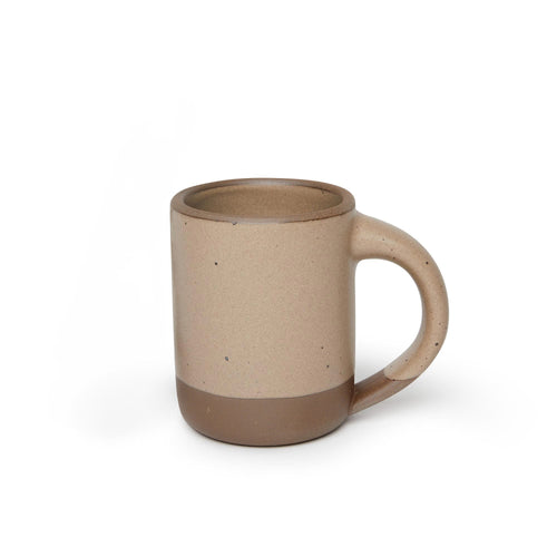 A medium sized ceramic mug with handle in a warm pale brown color featuring iron speckles and unglazed rim and bottom base.