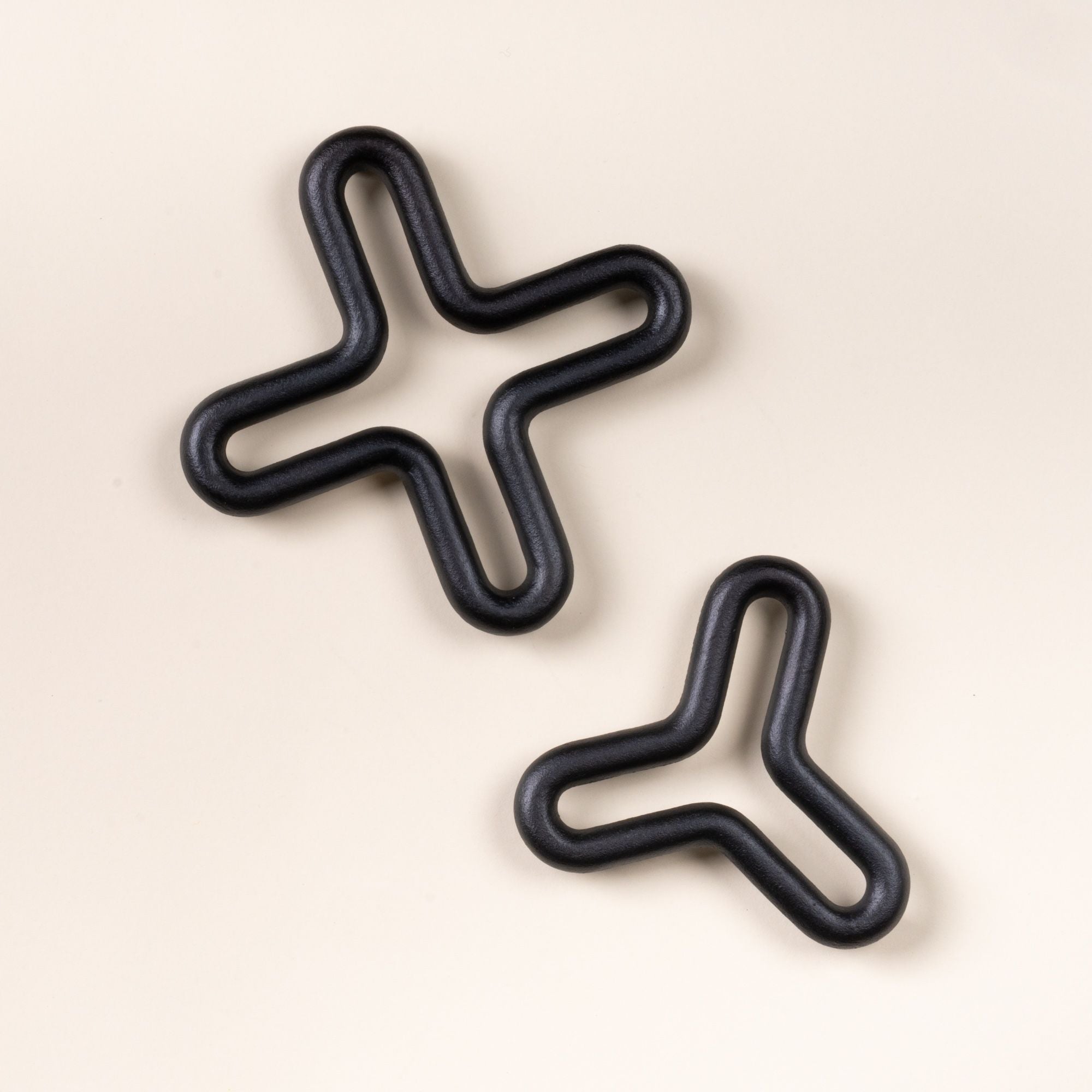 Two black wavy trivets shaped like a three-point and four-point star on a light neutral background.