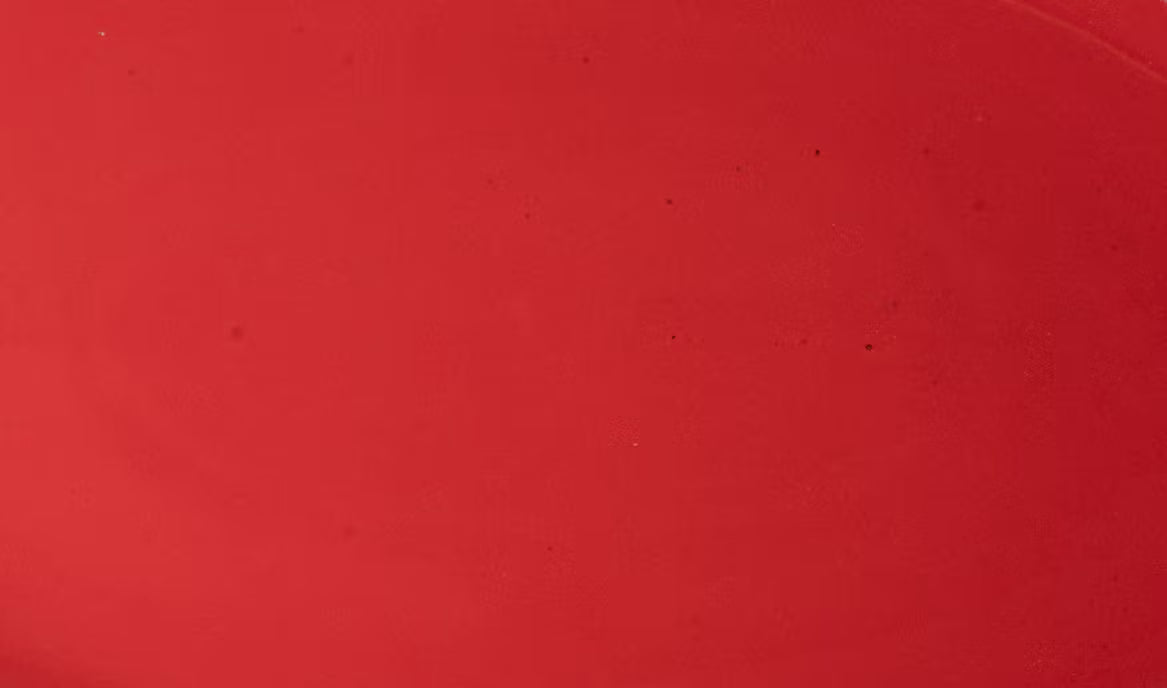 Closeup of a glossy red plate with subtle iron speckles