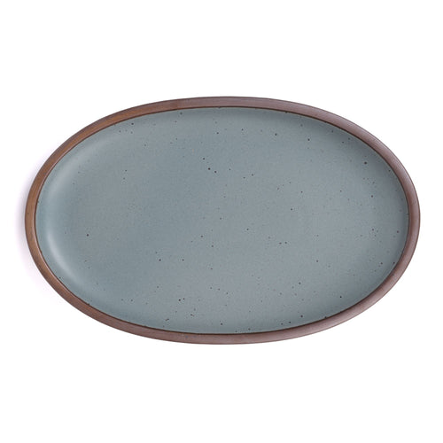A large oval ceramic platter in a blue-grey color featuring iron speckles and an unglazed rim