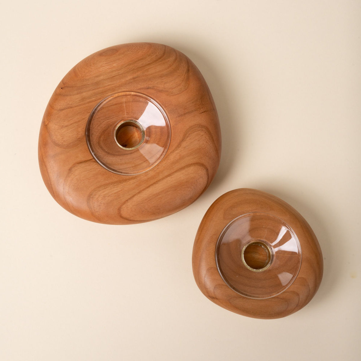 Top-down view of two round cherry wood candle holders in different sizes, each with a clear glass insert in the center, set against a neutral background.
