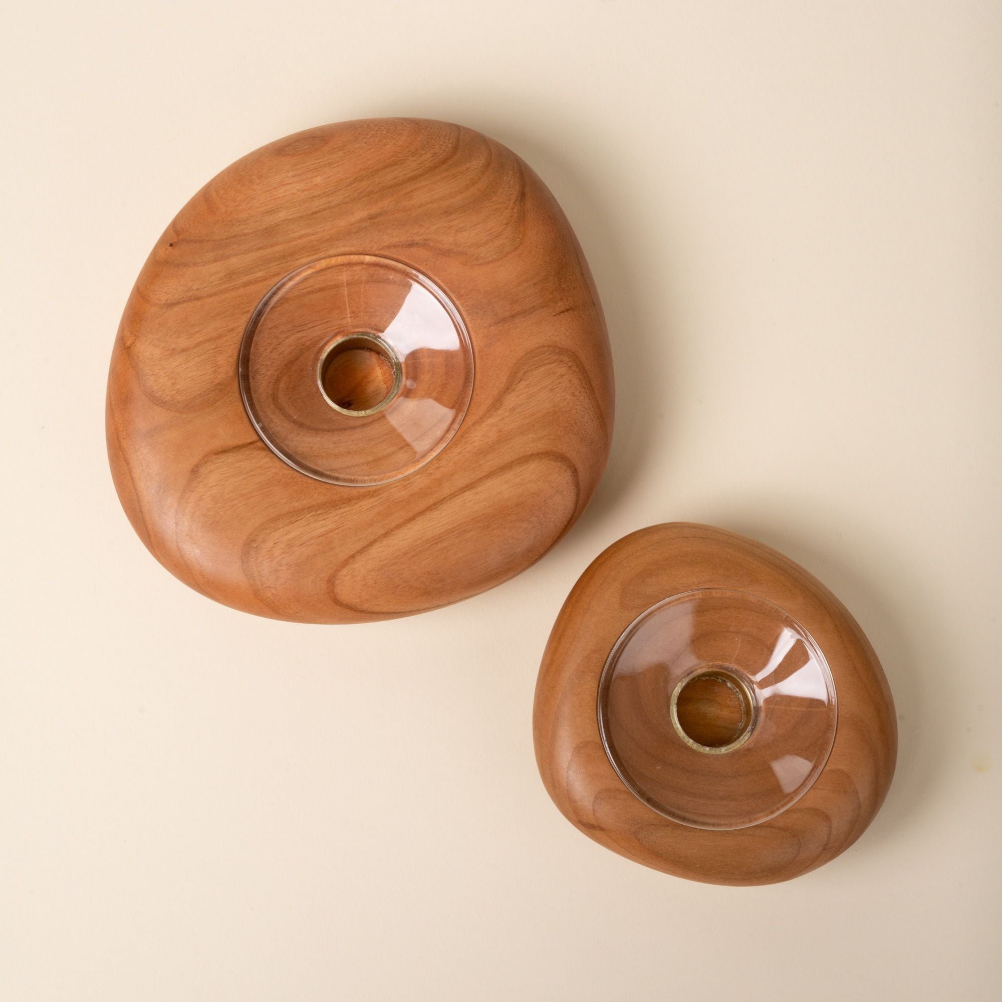 Top-down view of two round cherry wood candle holders in different sizes, each with a clear glass insert in the center, set against a neutral background.