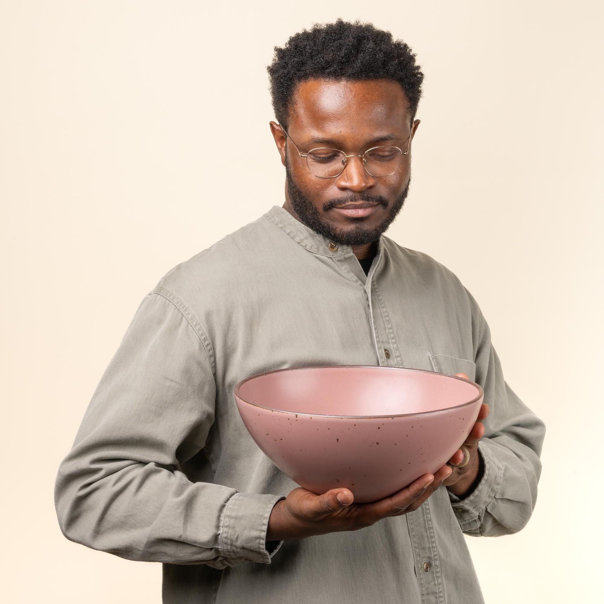 Demonta' holding a large ceramic mixing bowl in a dusty mauve pink color.