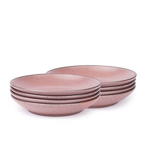 A stack of 8 large ceramic plates with a curved bowl edge in a dusty mauve pink color featuring iron speckles and an unglazed rim.