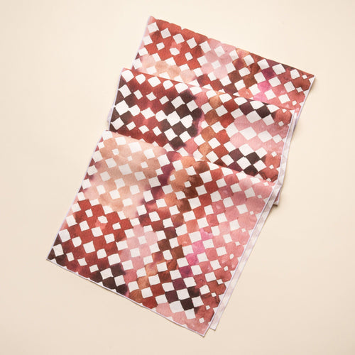 Watercolor diamond-patterned table runner in warm burgundy and pink tones