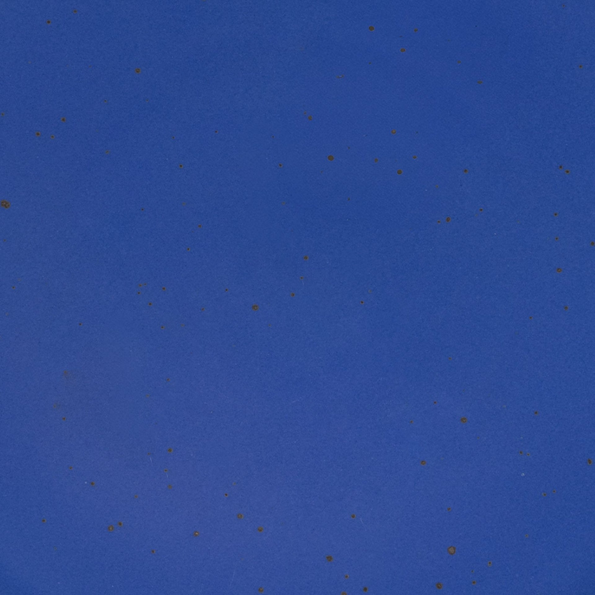 A closeup of a ceramic plate in a cobalt blue color with iron speckles throughout