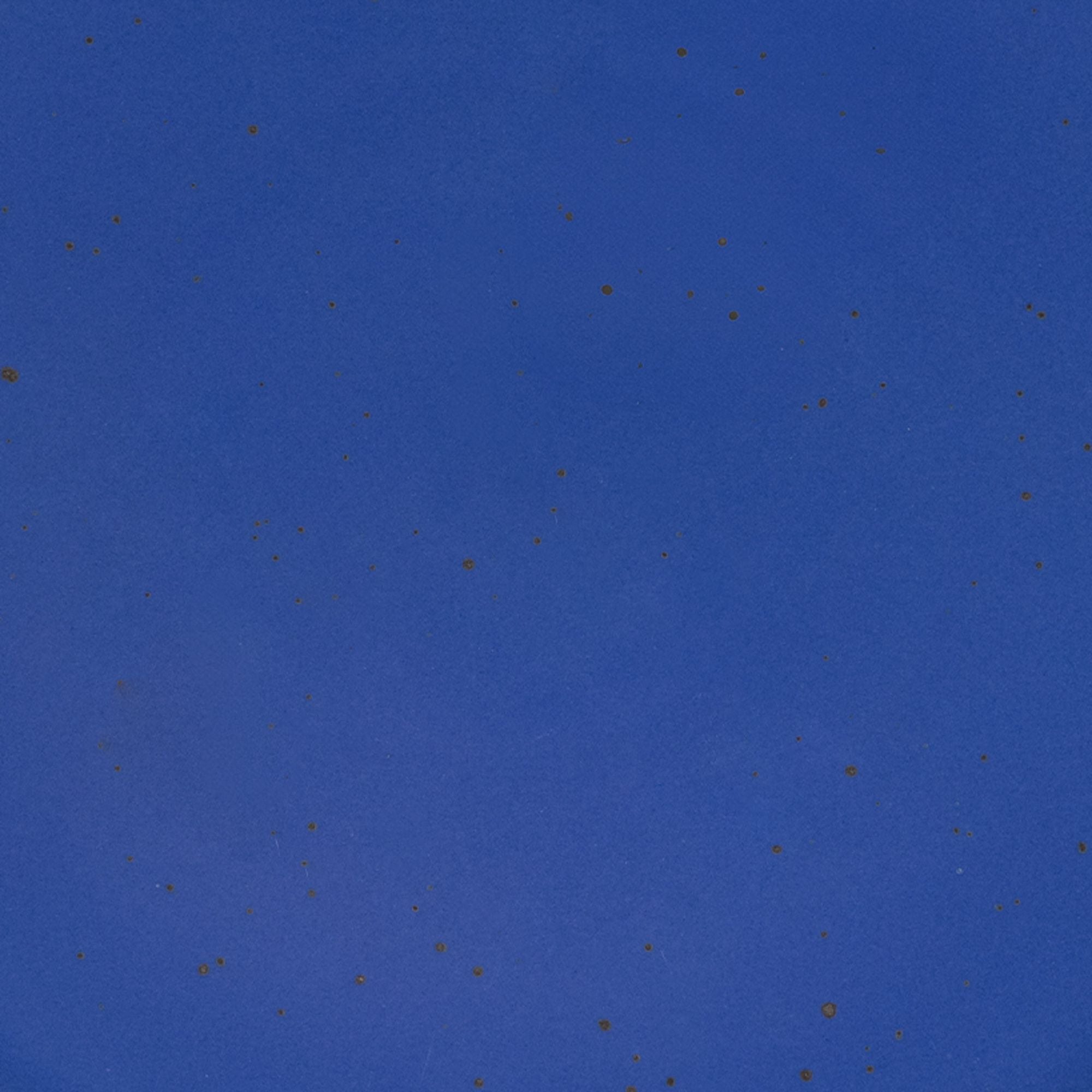 A closeup of a ceramic plate in a cobalt blue color with iron speckles throughout
