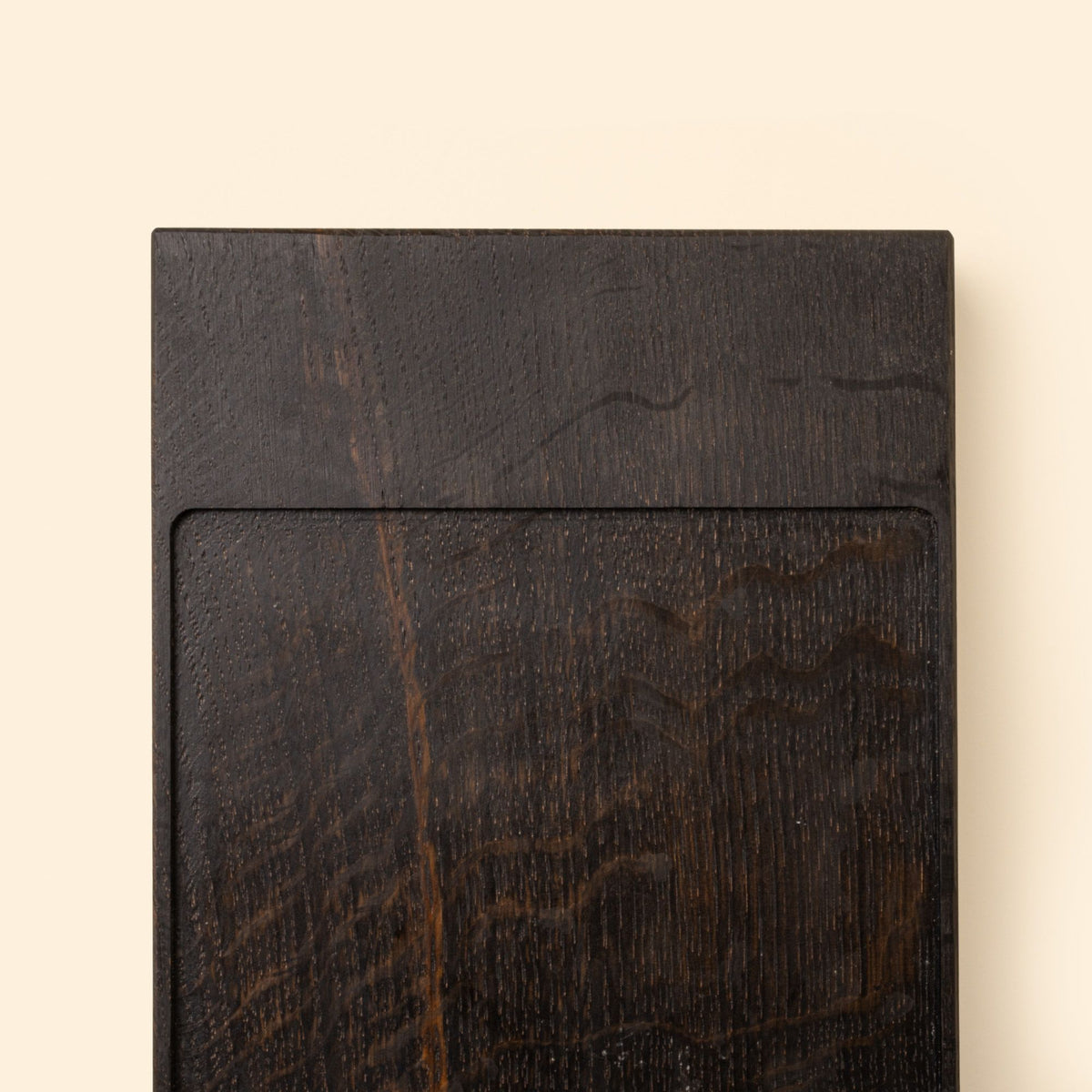 Close up of the end of a narrow rectangle of ebonized oak wood with a vertical groove at either end
