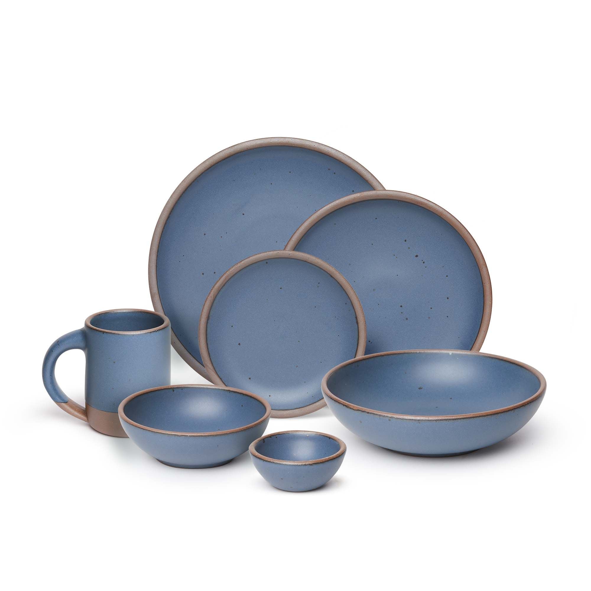 The Mug, bitty bowl, breakfast bowl, everyday bowl, cake plate, side plate and dinner plate paired together in a cool, medium blue color featuring iron speckles